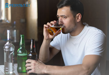 Мужчина сидит и пьет алкоголь